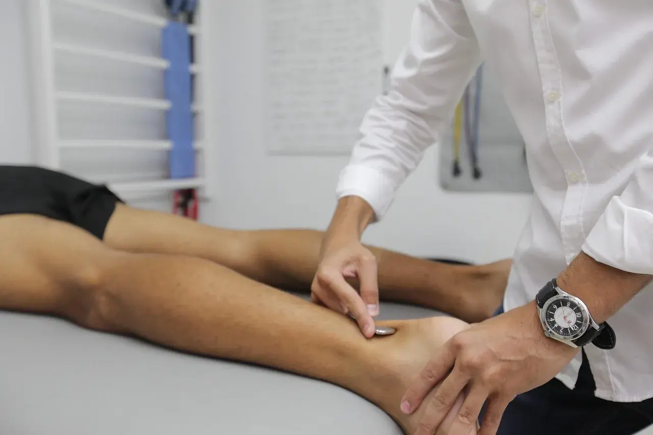 Fizjoterapeuta wykonuje zabieg na stopie pacjenta, co jest częścią rehabilitacji w ramach prewencji rentowej ZUS.