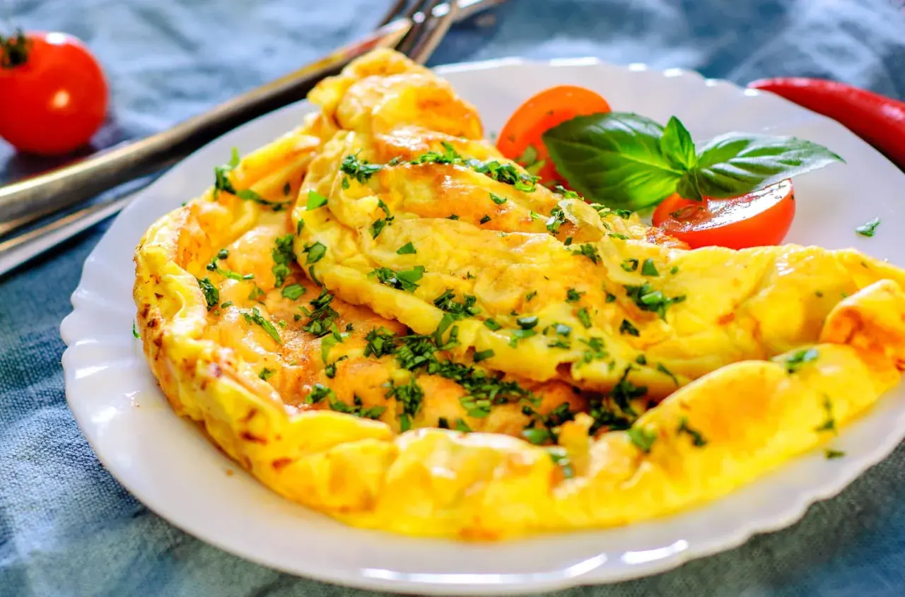 Une omelette dorée et moelleuse, garnie de persil frais. Une recette simple et rapide pour un repas savoureux.