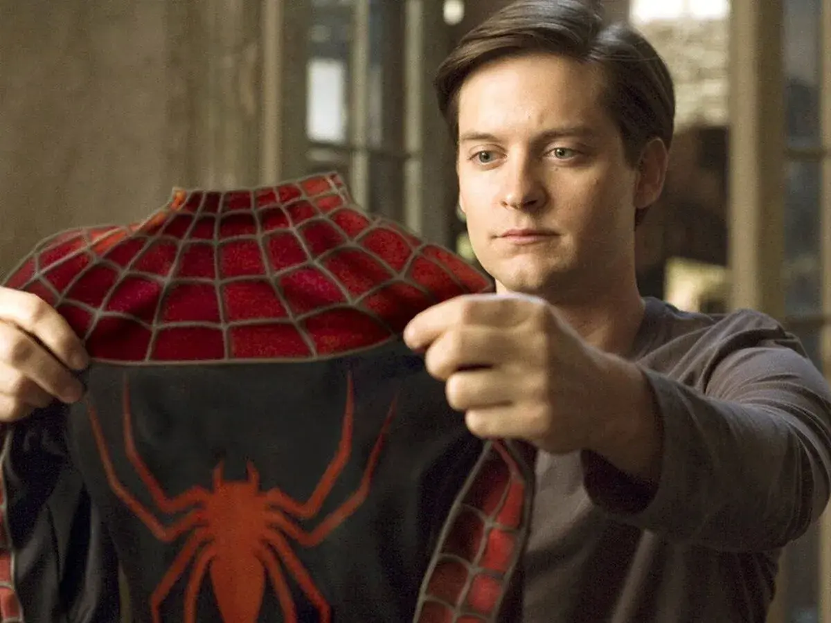 Tobey Maguire examine le costume de Spider-Man, un moment clé dans les films avec Tobey Maguire.