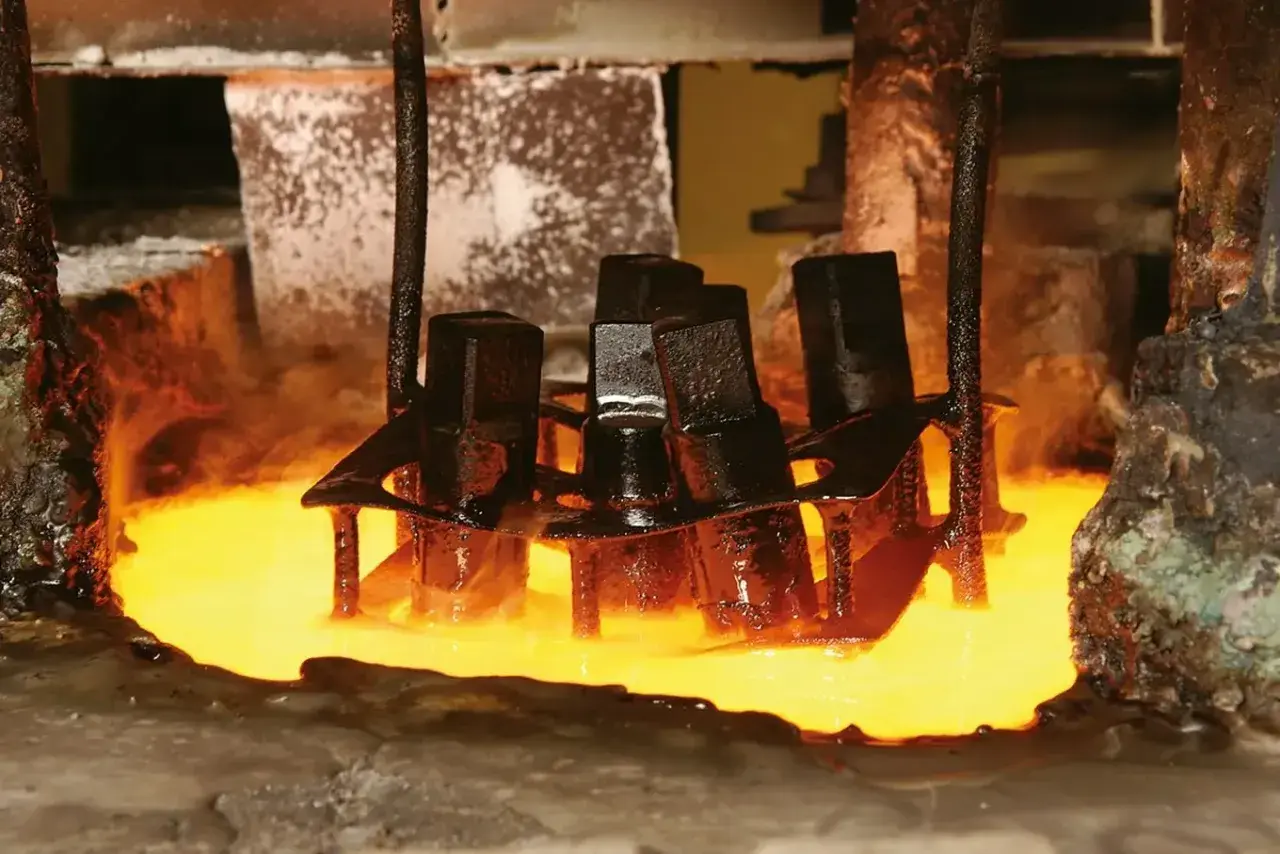 Metalowe elementy zanurzane w rozgrzanym płynie, proces hartowania. Para unosi się wokół.