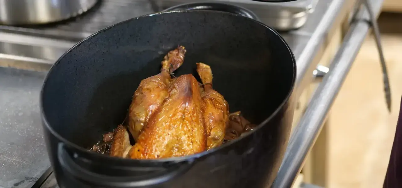 Une poularde dorée mijote dans une cocotte. Quel vin avec une poularde ? Un blanc de Bourgogne ou un rouge léger serait parfait.