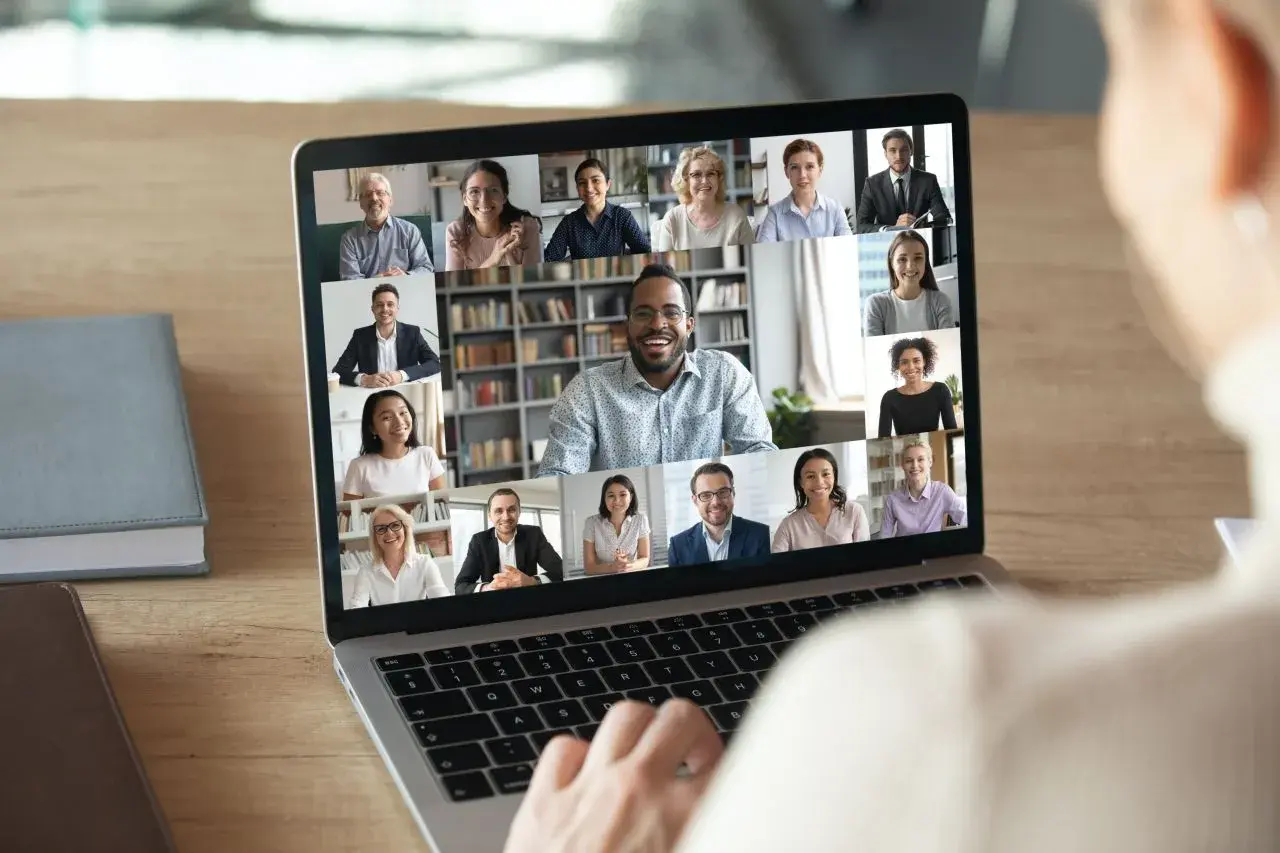 Ein Team bespricht sich per Videoanruf. Viele Gesichter lächeln vom Laptop-Bildschirm, was die Flexibilität von jobs im home office zeigt.