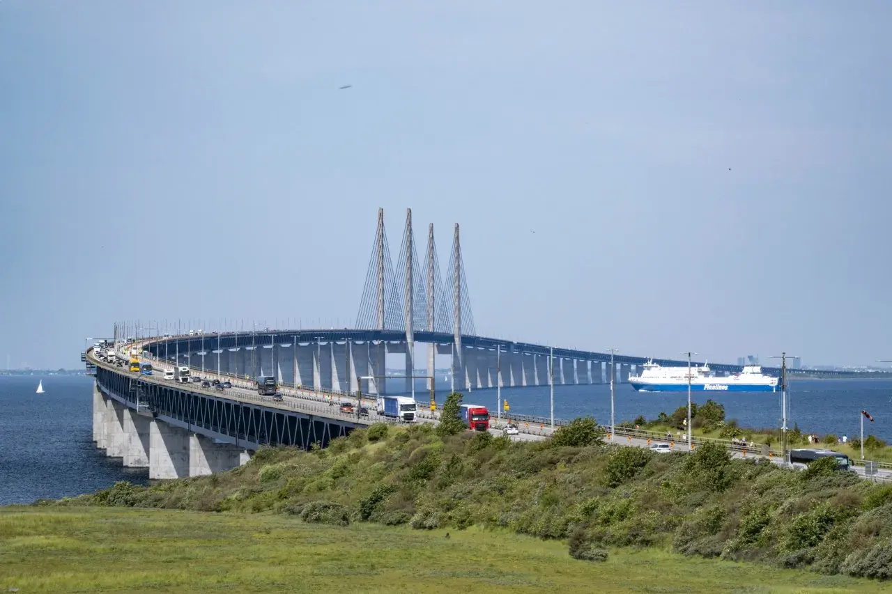 Öresundsbron, bron till Danmark, med bilar och en färja i Öresund.