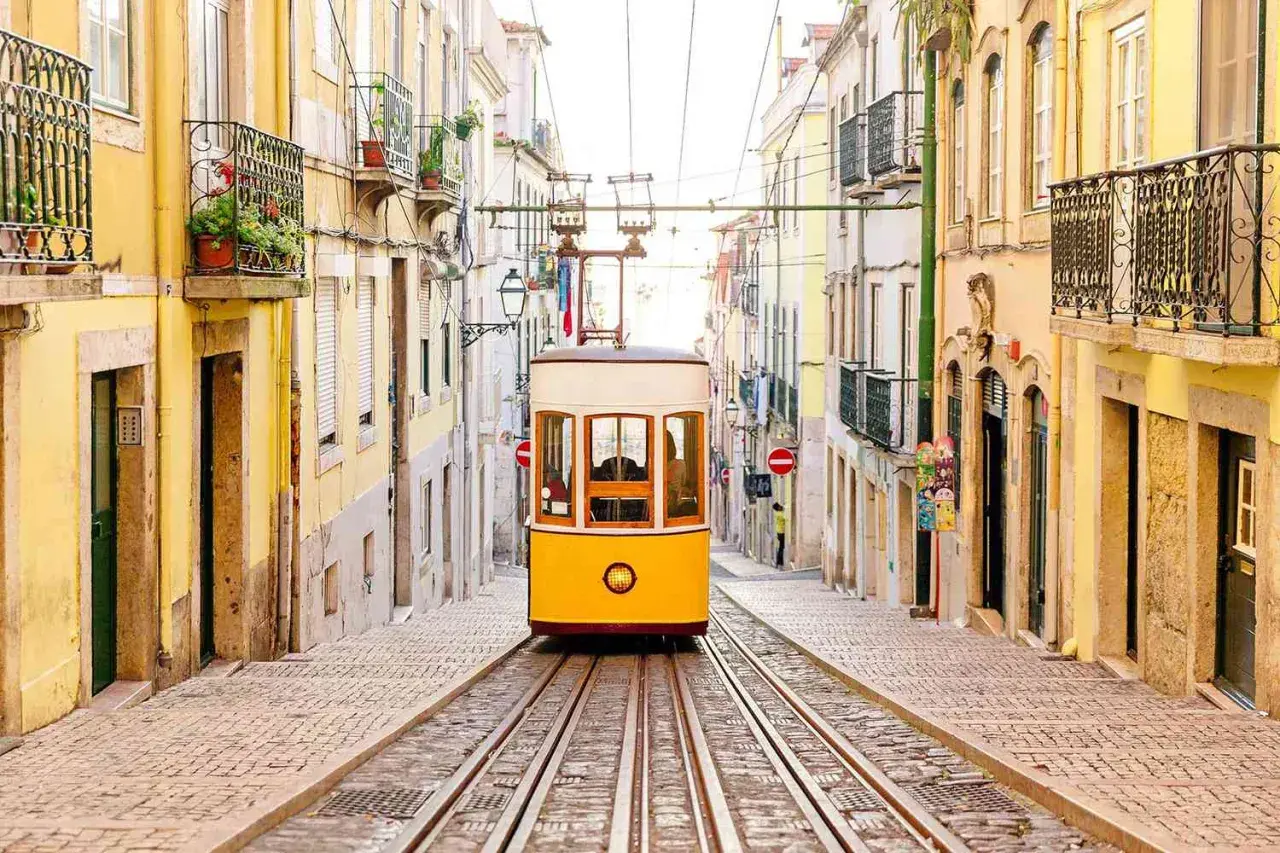 A classic yellow tram ascends a steep, cobblestone street lined with colorful buildings, a perfect scene for one day in Lisbon.