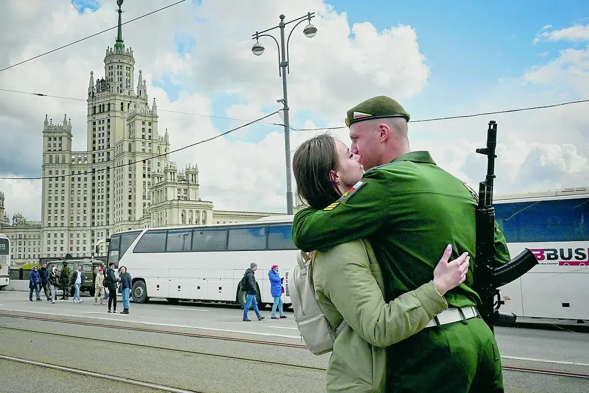Żołnierz w zielonym mundurze, z karabinem na ramieniu, całuje ukochaną na tle moskiewskiego drapacza chmur. To nie jest sposób, jak podrywa ukrainiec, ale piękny moment pożegnania.