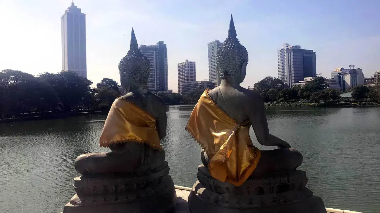 Dwie posągi Buddy z widokiem na nowoczesną panoramę stolicy Sri Lanki.