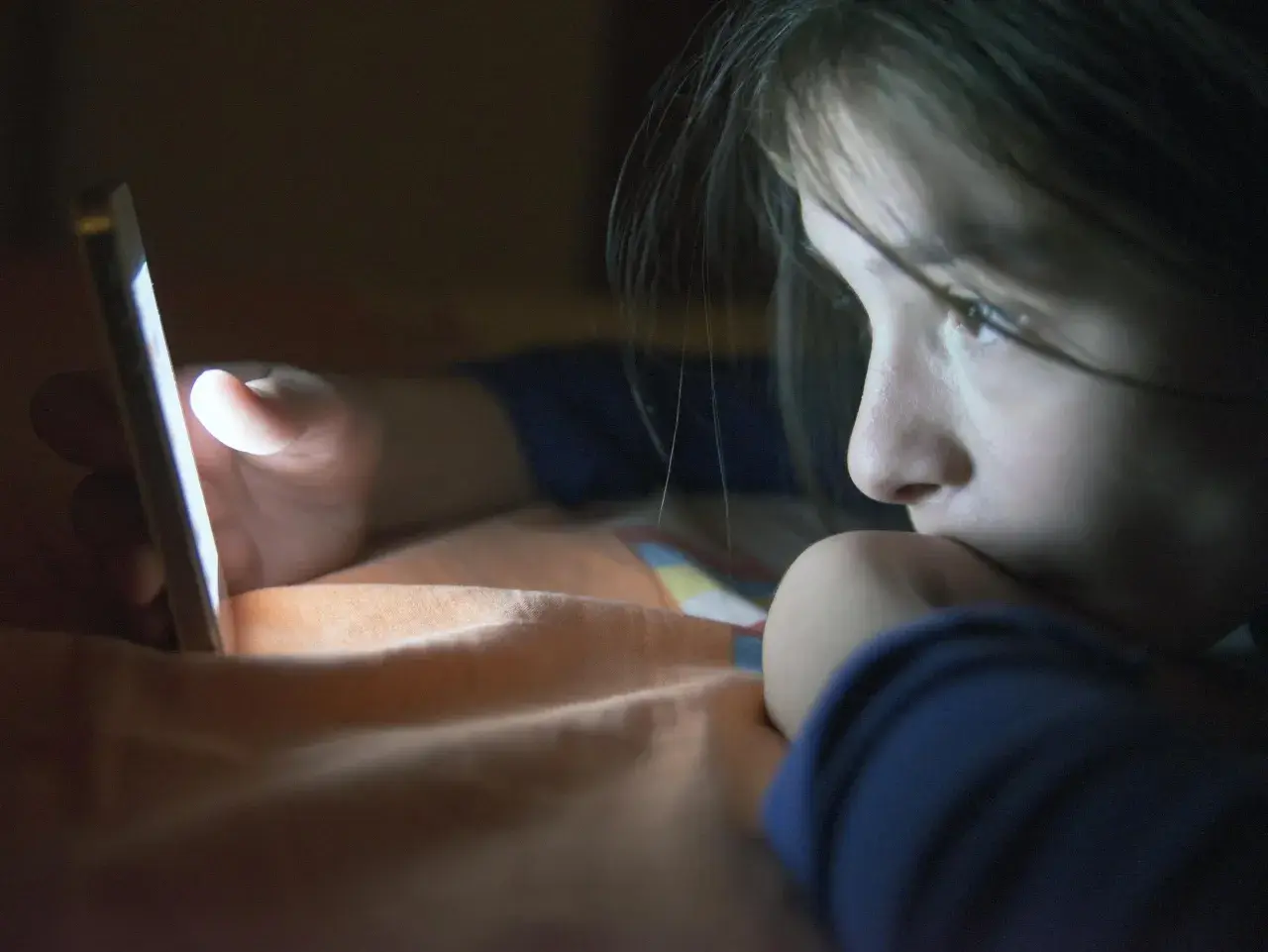 Dziecko wpatrzone w ekran telefonu. Jak influencerzy radzą sobie z hejtem skierowanym w stronę ich dzieci?