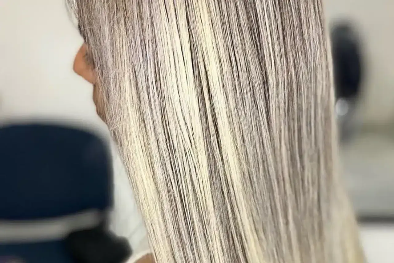 Cabello largo y liso con mechas rubias cenizas, luciendo un estilo moderno y elegante.