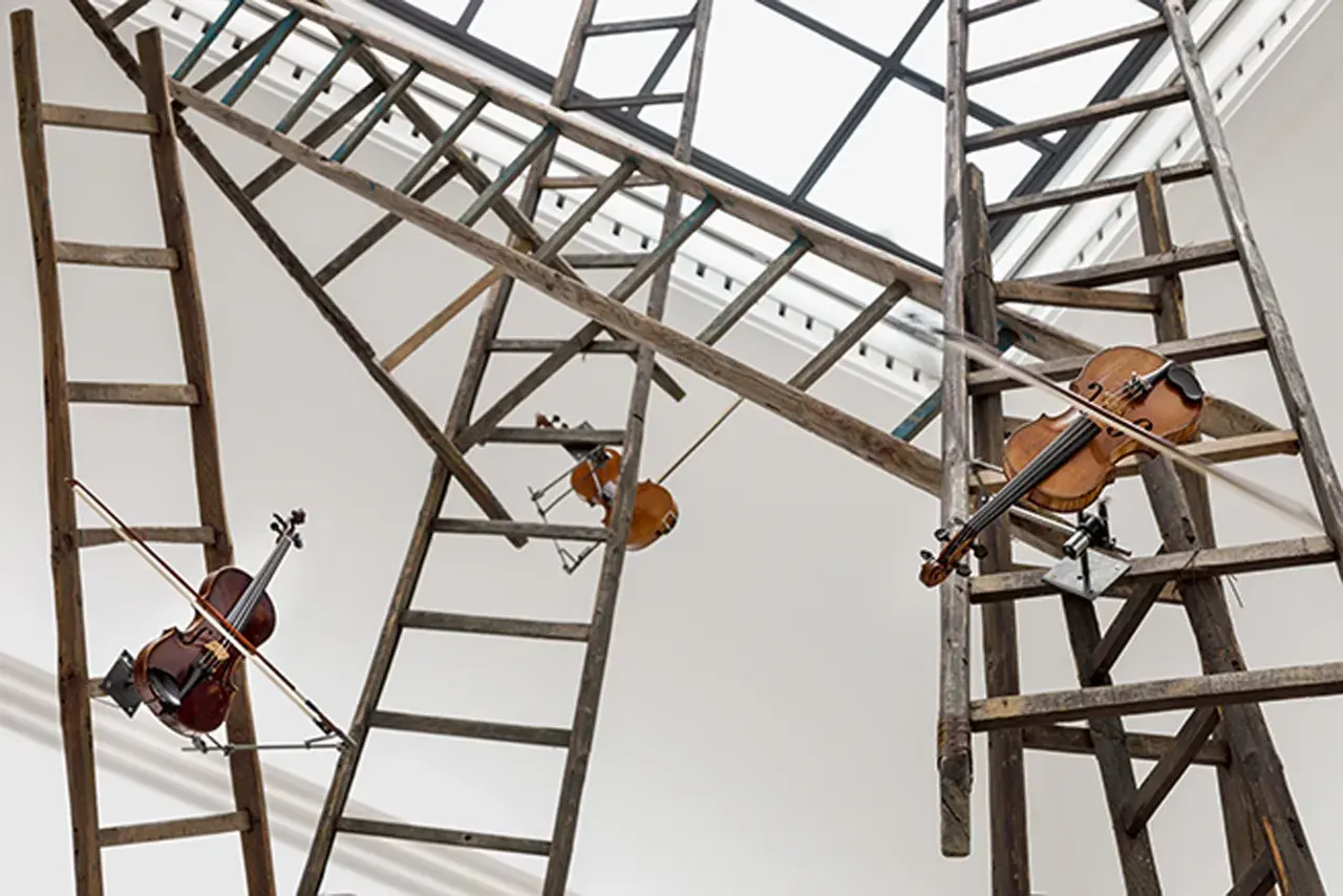 Der Turm der namenlosen Rebecca Horn: Geigen hängen an Holzleitern, die sich im Raum kreuzen, als würden sie eine Melodie der Vergänglichkeit spielen.