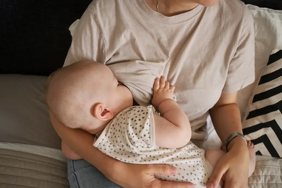 Un neonato si nutre al seno, un momento intimo che celebra il legame tra madre e figlio. Il ciclo della vita continua con l'allattamento.