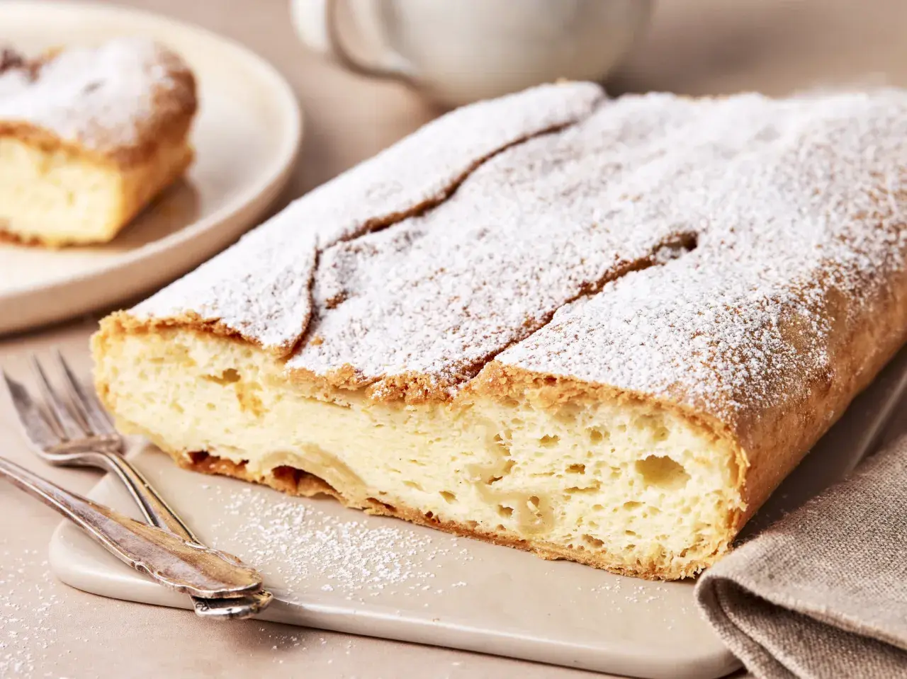 Ein köstlicher Topfenstrudel, bestäubt mit Puderzucker, wartet darauf, probiert zu werden. Dieses Topfenstrudel Rezept ist ein Genuss!