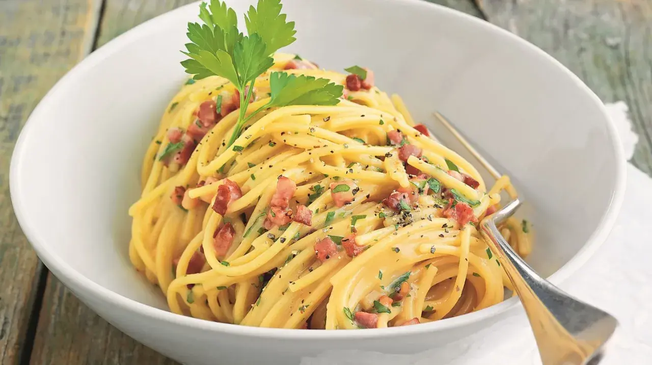 Ein Teller Spaghetti mit cremiger Sauce, Speckwürfeln und Petersilie. Ein Klassiker: Schinken Carbonara.