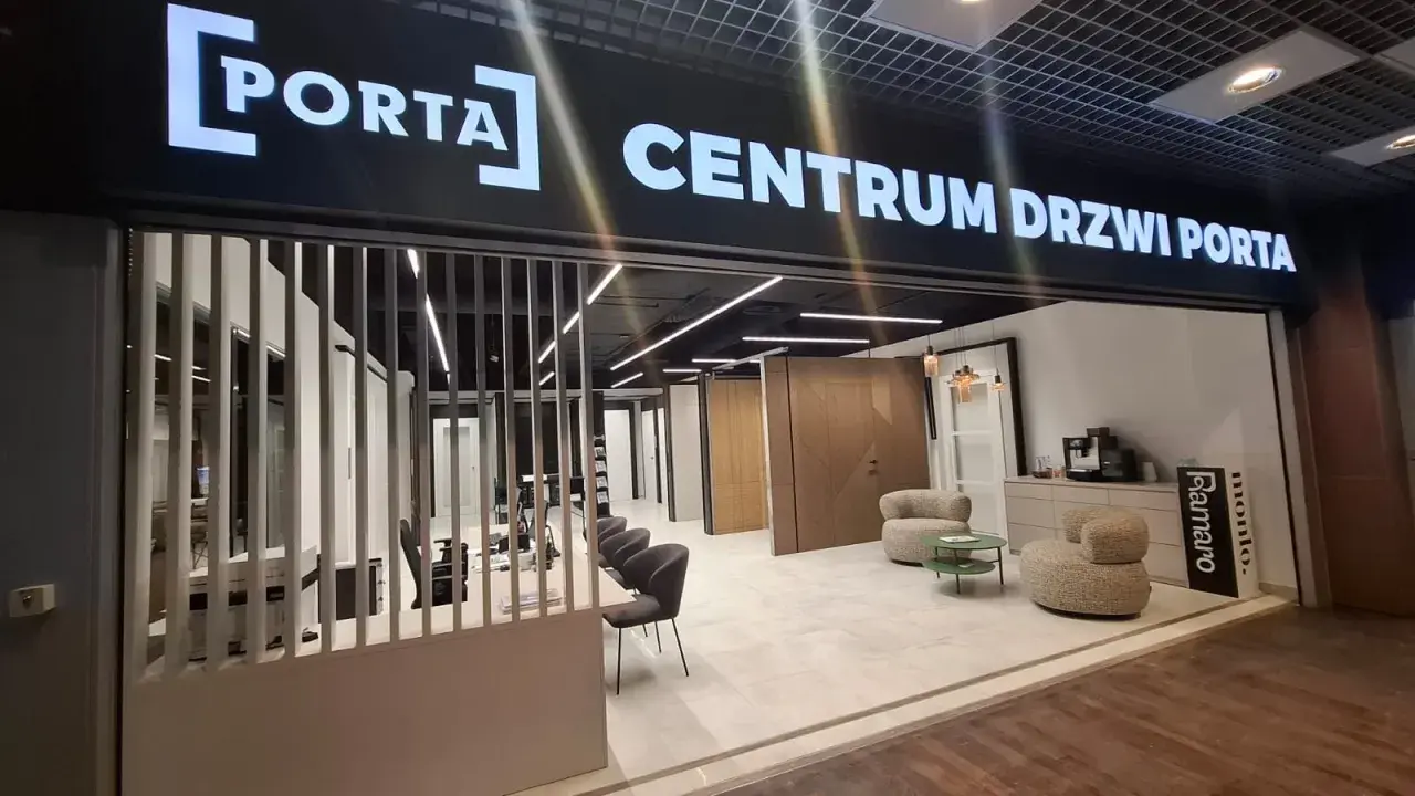 Salon drzwi i okien PORTA z ekspozycją drzwi, meblami i ekspressem do kawy.