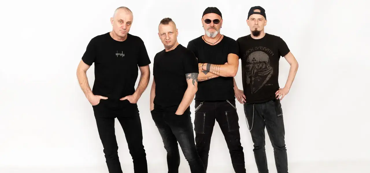 Czterech mężczyzn w czarnych ubraniach, tworzących zespół. Jeden z nich ma na koszulce napis "simply", inny koszulkę z logo Black Sabbath.