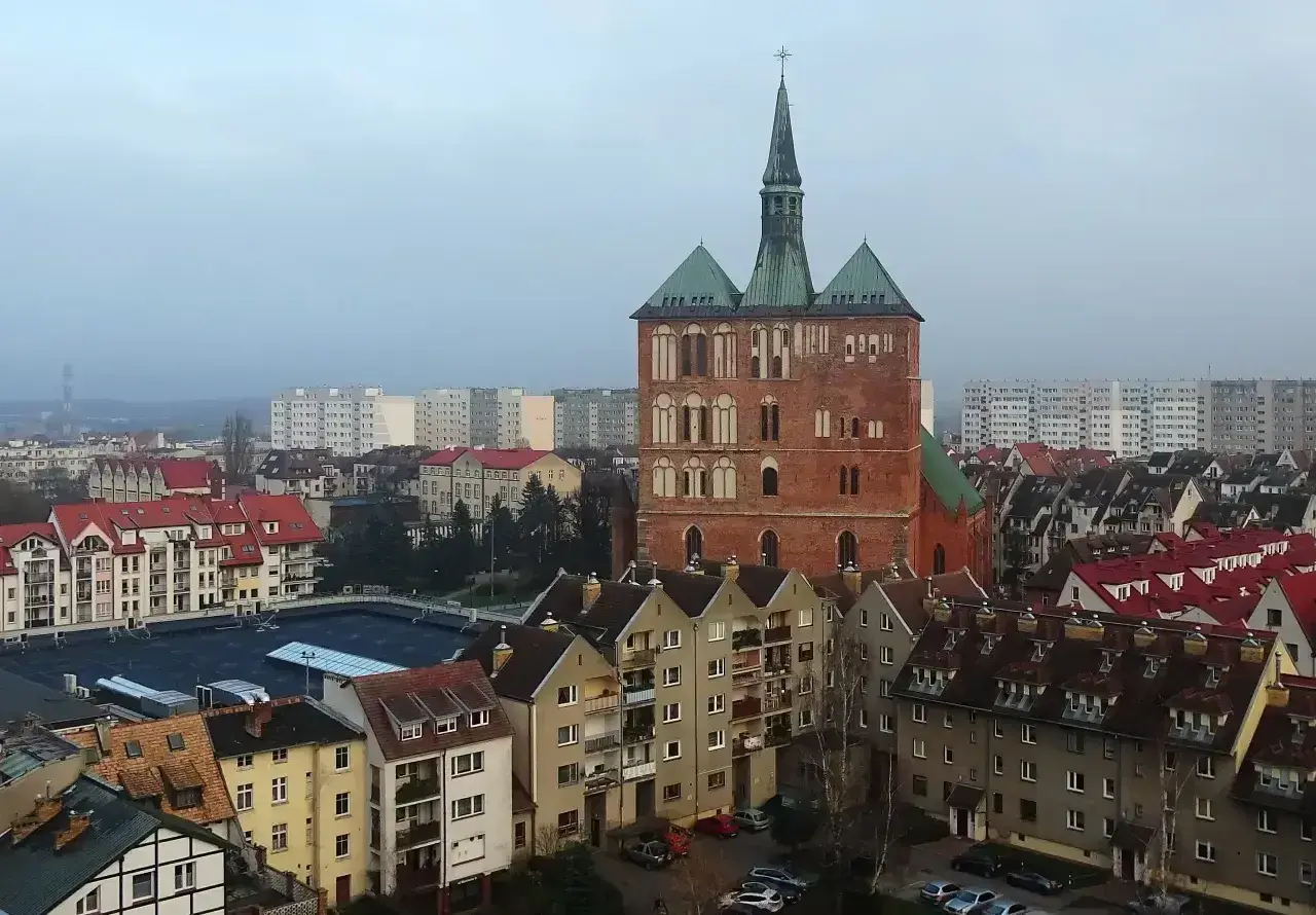 Widok na ceglaną wieżę kościoła i zabudowania miejskie Kołobrzegu.