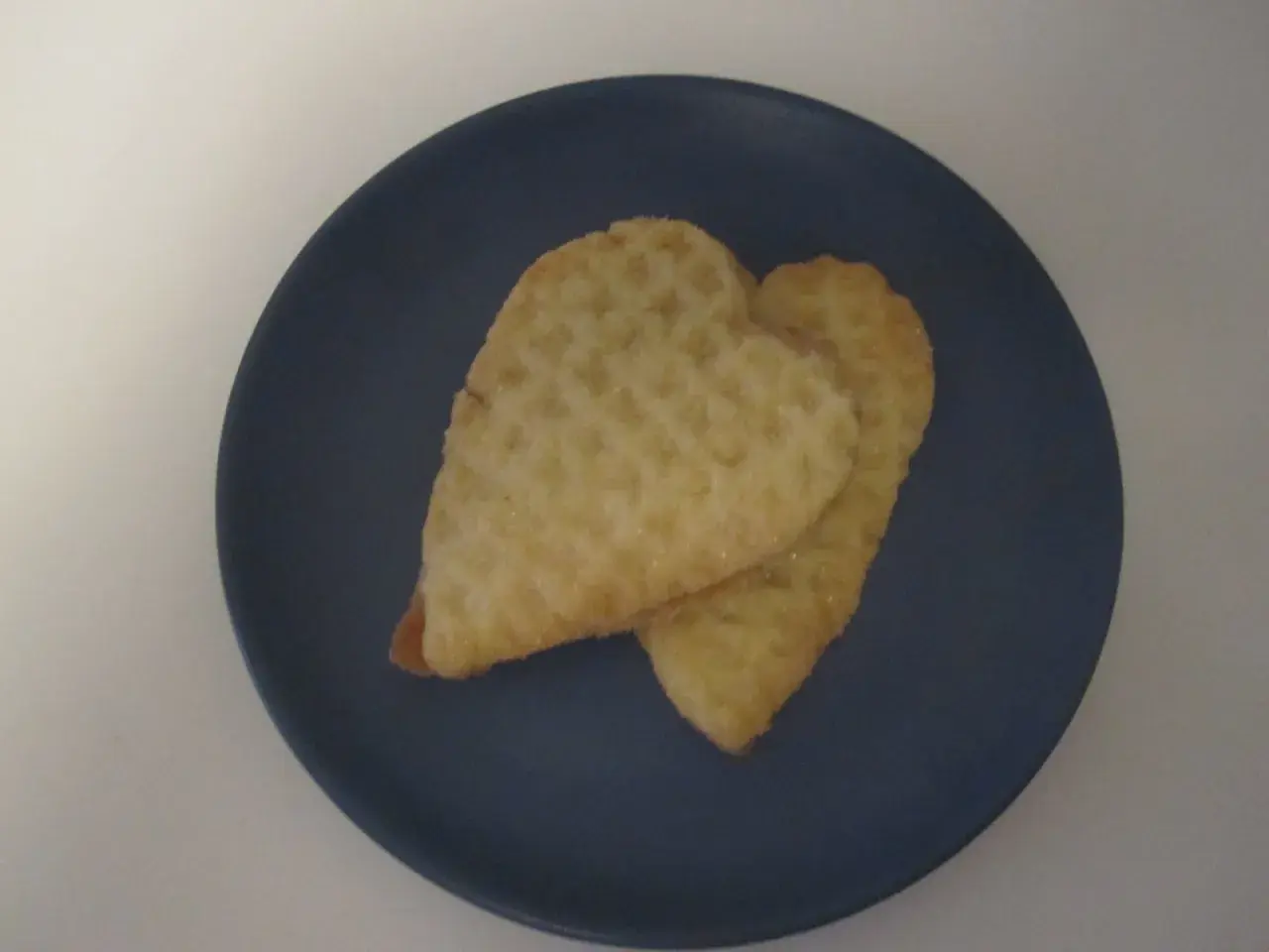 Två hjärtformade kex med socker på en mörkblå tallrik. Perfekta för parisare recept.