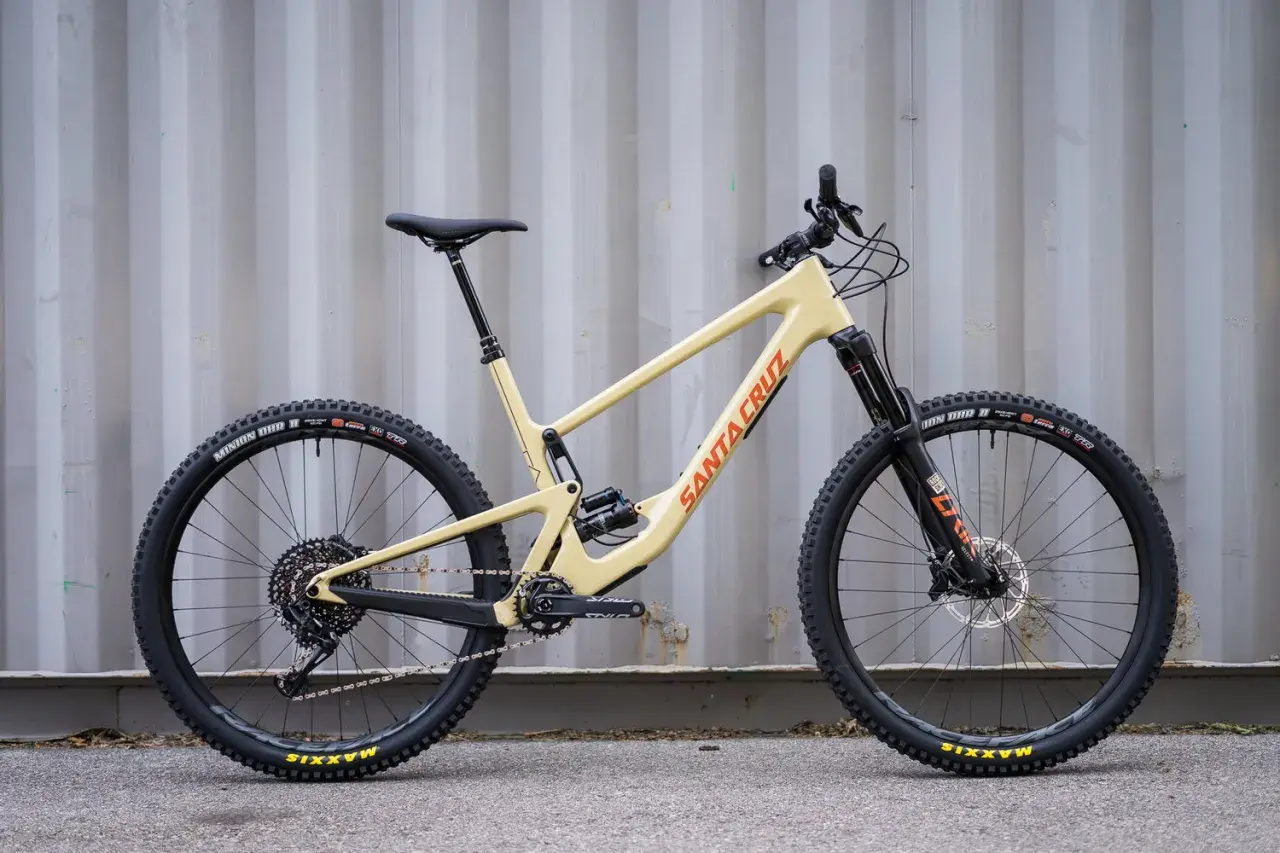 A tan 2020 Santa Cruz Hightower mountain bike with black wheels and orange "Santa Cruz" lettering.