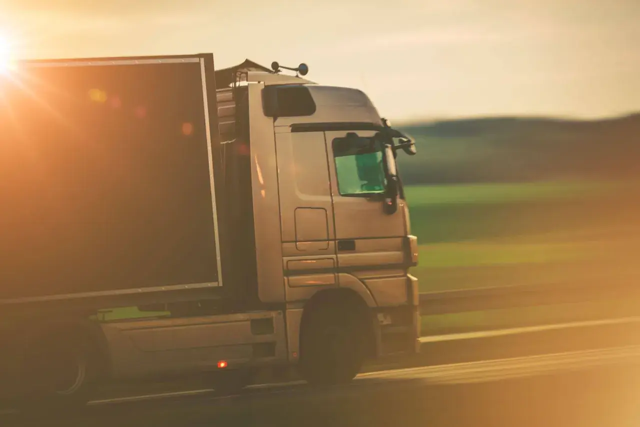 Ciężarówka w ruchu, symbolizująca profesjonalizm i sprawność w transporcie, gdzie kluczowe jest użyczenie certyfikatu kompetencji zawodowych.
