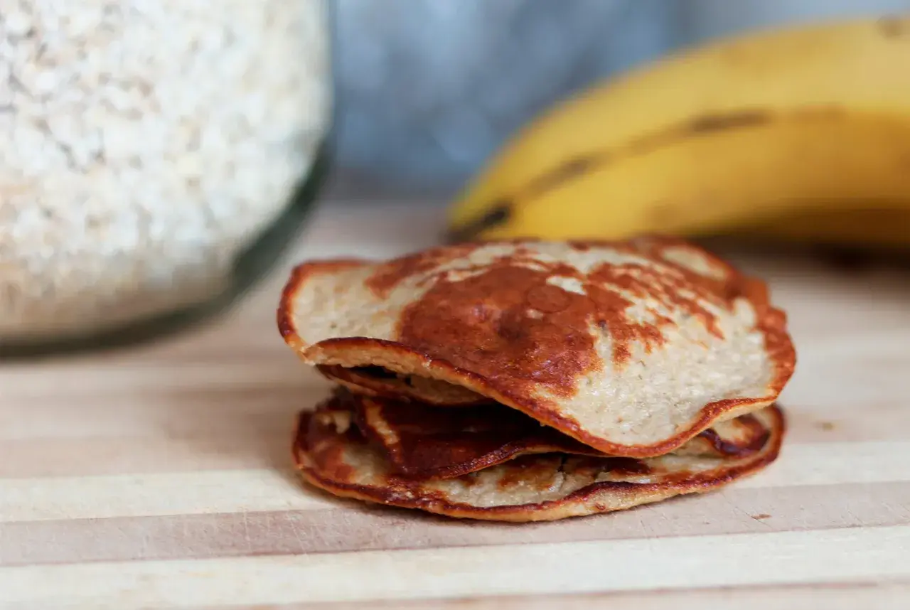 En hög med gyllenbruna bananpannkakor, redo att avnjutas. Ett enkelt bananpannkaka recept för en god frukost.