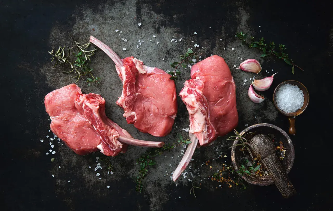 Trois belles côtes de veau crues, prêtes à être assaisonnées avec du sel, de l'ail et des herbes aromatiques.