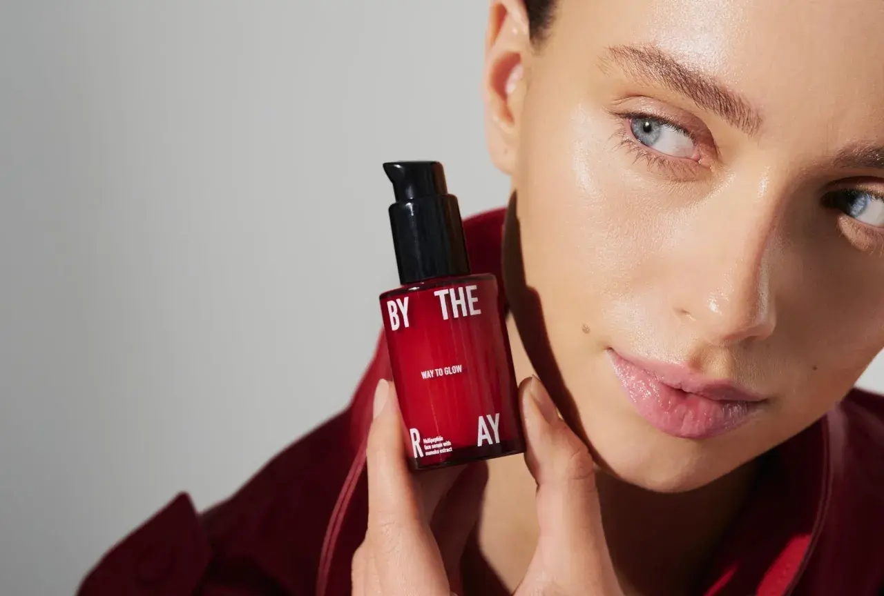 Kobieta z serum z peptydami w kosmetyce. Czerwona buteleczka z napisem "WAY TO GLOW" i "multipeptide face serum".