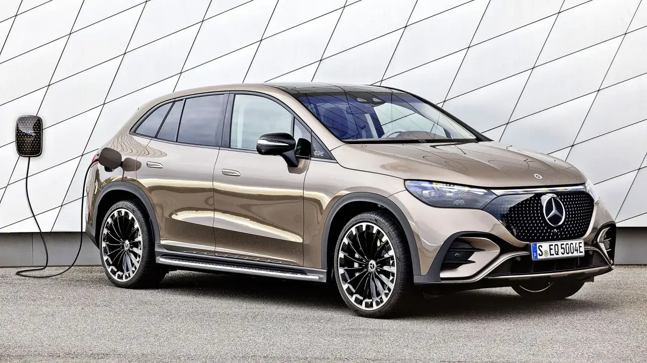 Brązowy Mercedes EQC na ładowaniu przy nowoczesnej ścianie. Stylowy SUV z elektrycznym napędem gotowy do drogi.