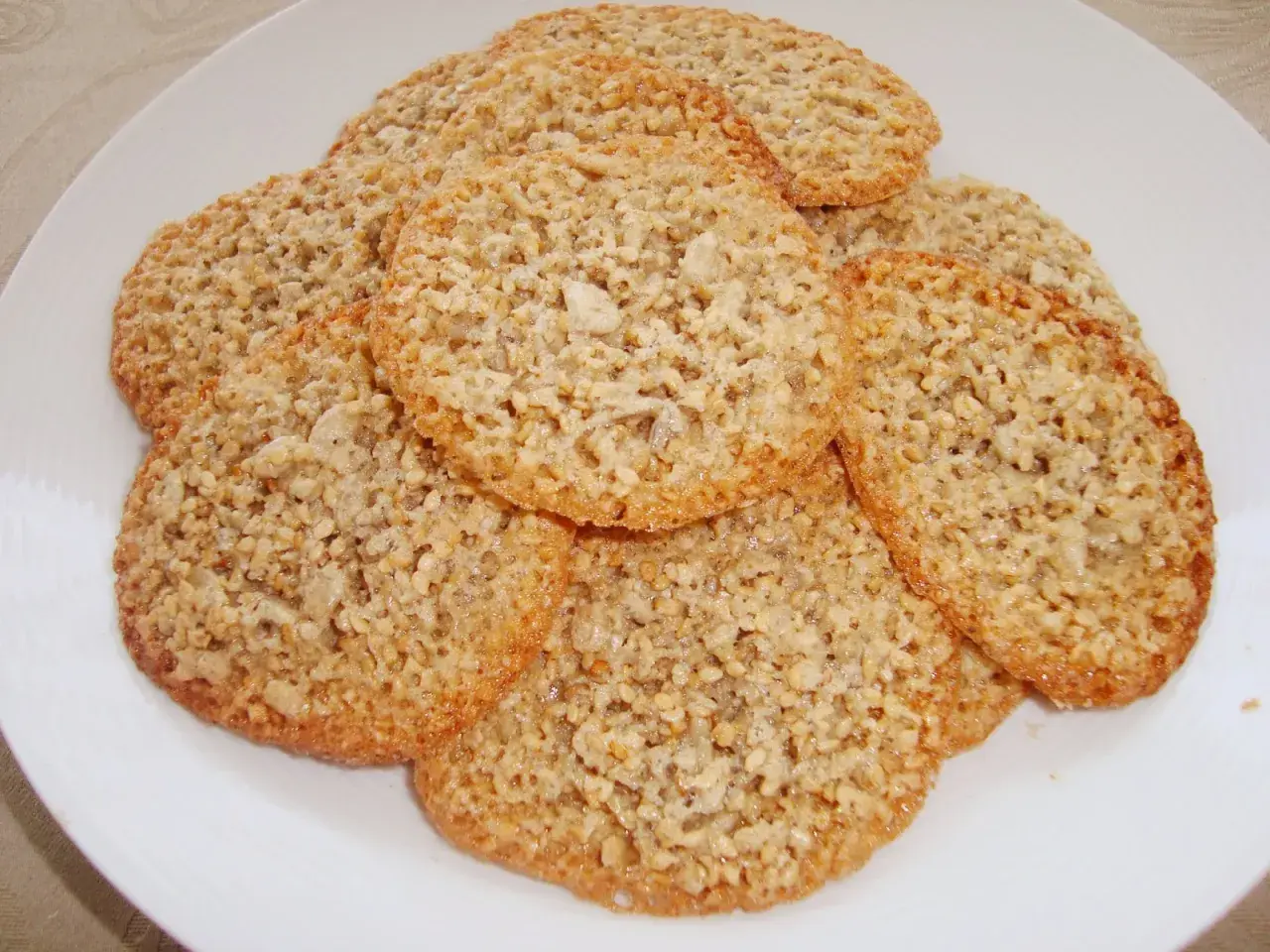 En hög med krispiga, gyllene glutenfria havreflarn på en vit tallrik. Perfekta för fikat!