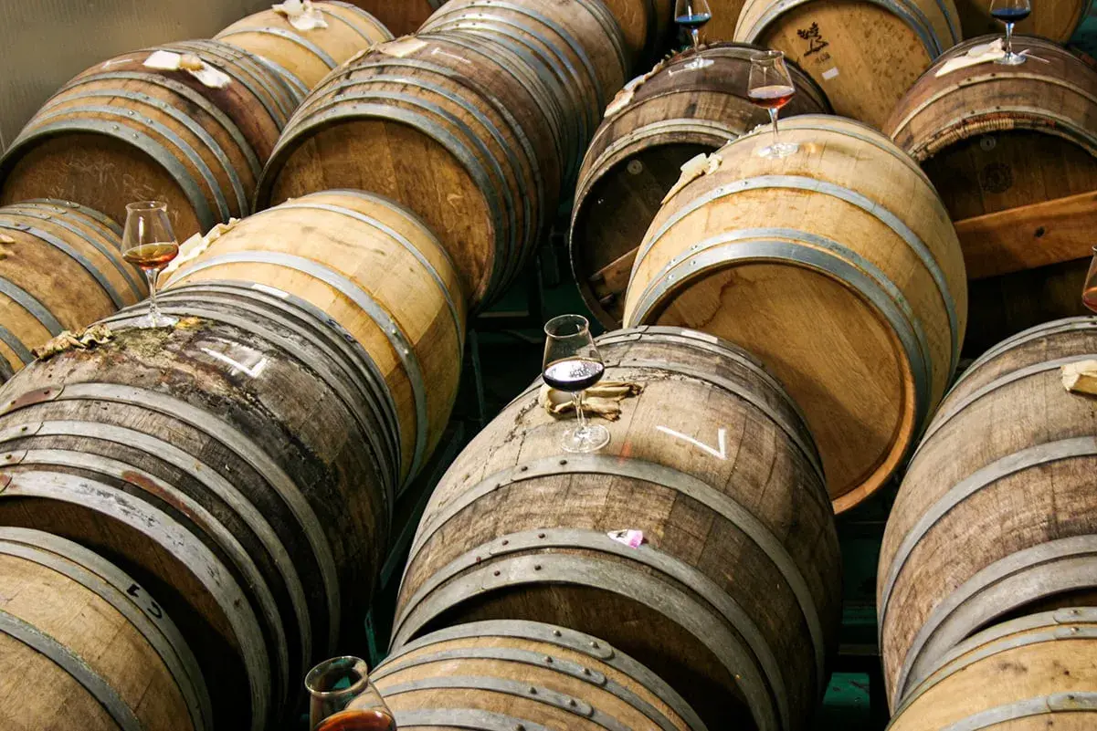 Botti di legno impilate, alcune con bicchieri di birra in attesa di essere degustate.