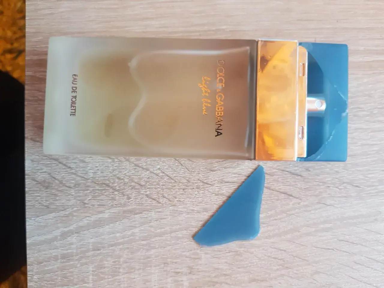 Perfumy Dolce & Gabbana Light Blue, w odcieniu niebieskim, na drewnianym tle.