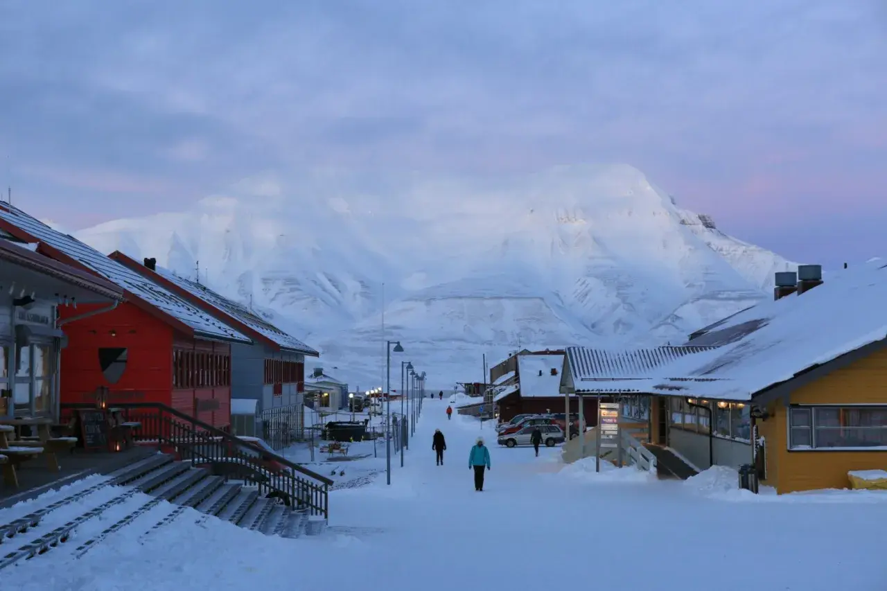 Śnieżna ulica w Longyearbyen, najwyżej położonym mieście na świecie, z górami w tle.