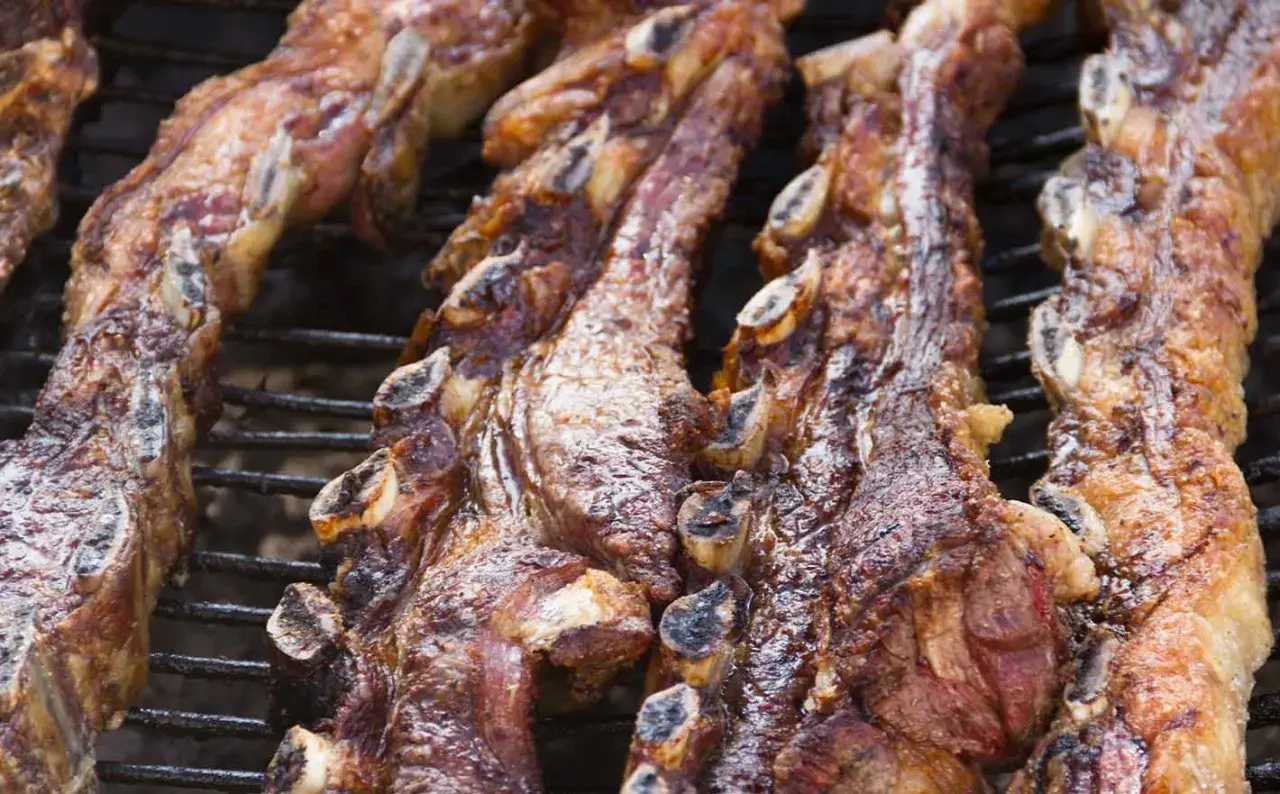 Costillas de churrasco al horno, doradas y jugosas, listas para disfrutar en una parrilla.