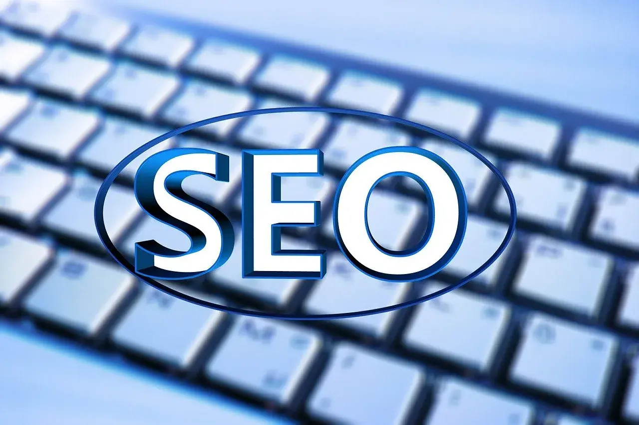 Niebieskie litery "SEO" na tle klawiatury. Unikaj black hat seo, postaw na uczciwe pozycjonowanie.