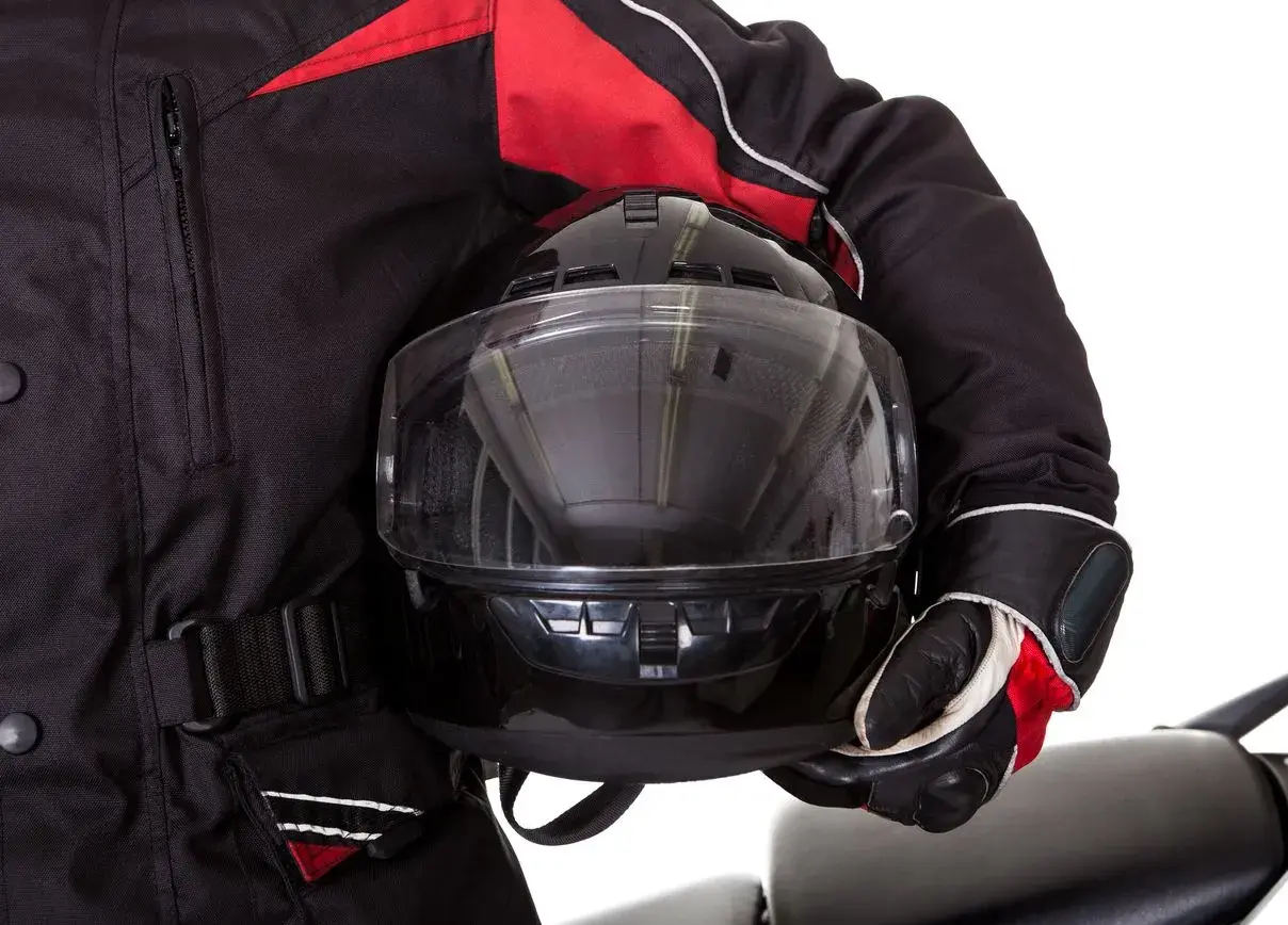 Motociclista con casco negro y chaqueta roja. Aprende como poner pinlock para evitar vaho.