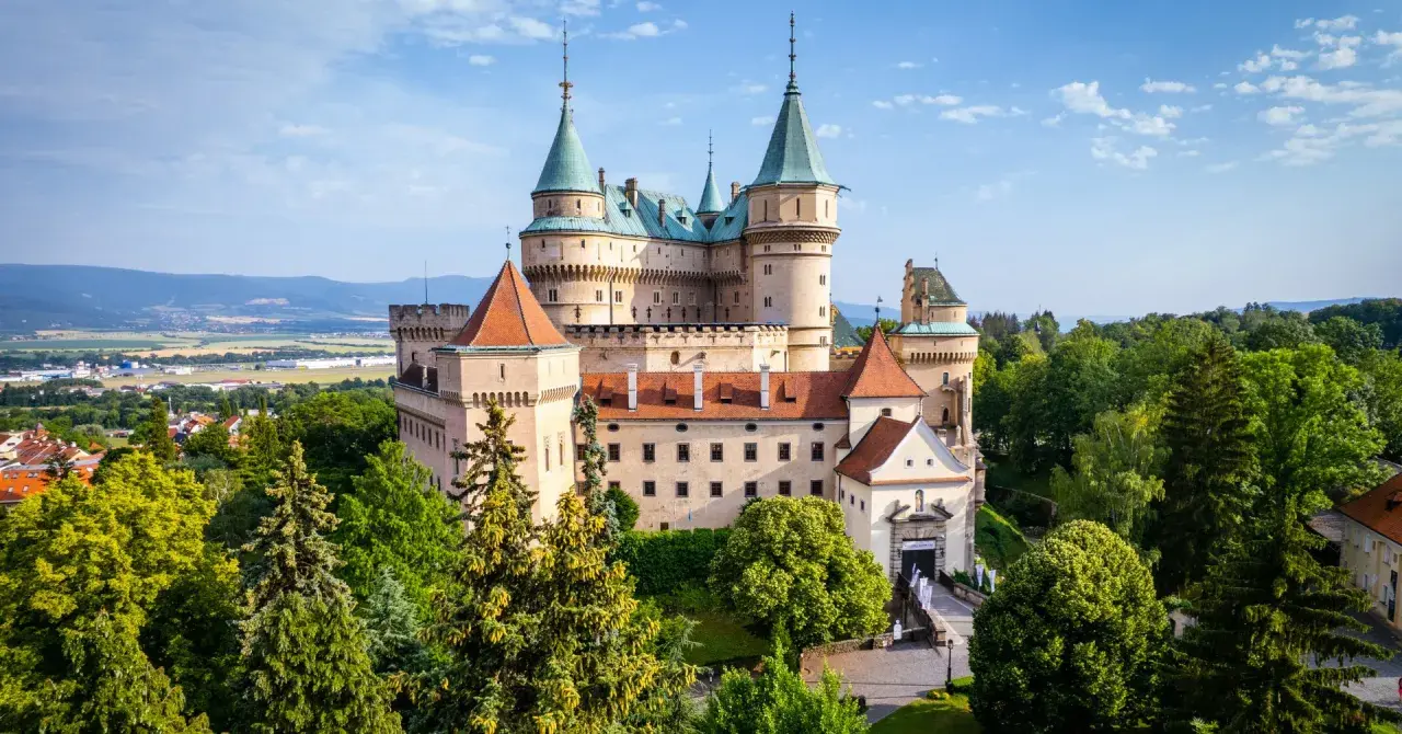 Majestatyczny zamek Bojnice, jeden z najpiękniejszych zamków na Słowacji, otoczony zielenią.