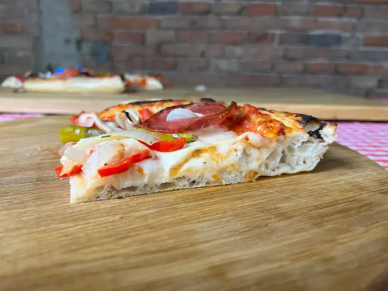 Ein Stück Pizza mit original italienischem Pizzateig Rezept Blech, belegt mit Salami, Paprika und Zwiebeln.