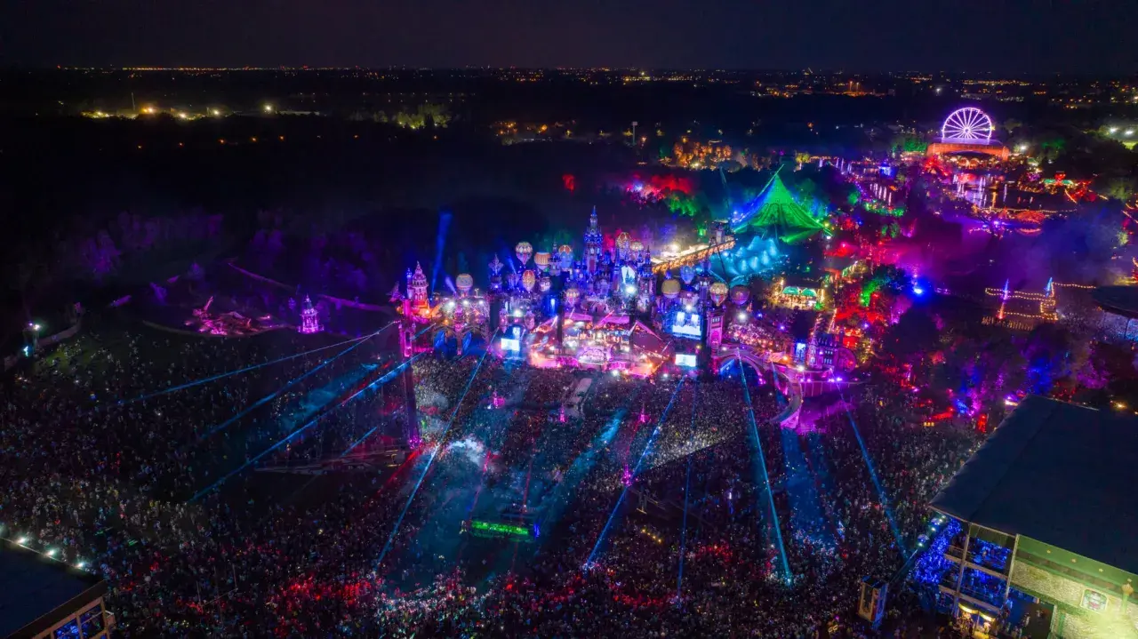 Nocny festiwal Tomorrowland 2026 w pełni. Tłumy ludzi, kolorowe światła, sceny w kształcie zamków i latające balony tworzą magiczną atmosferę.