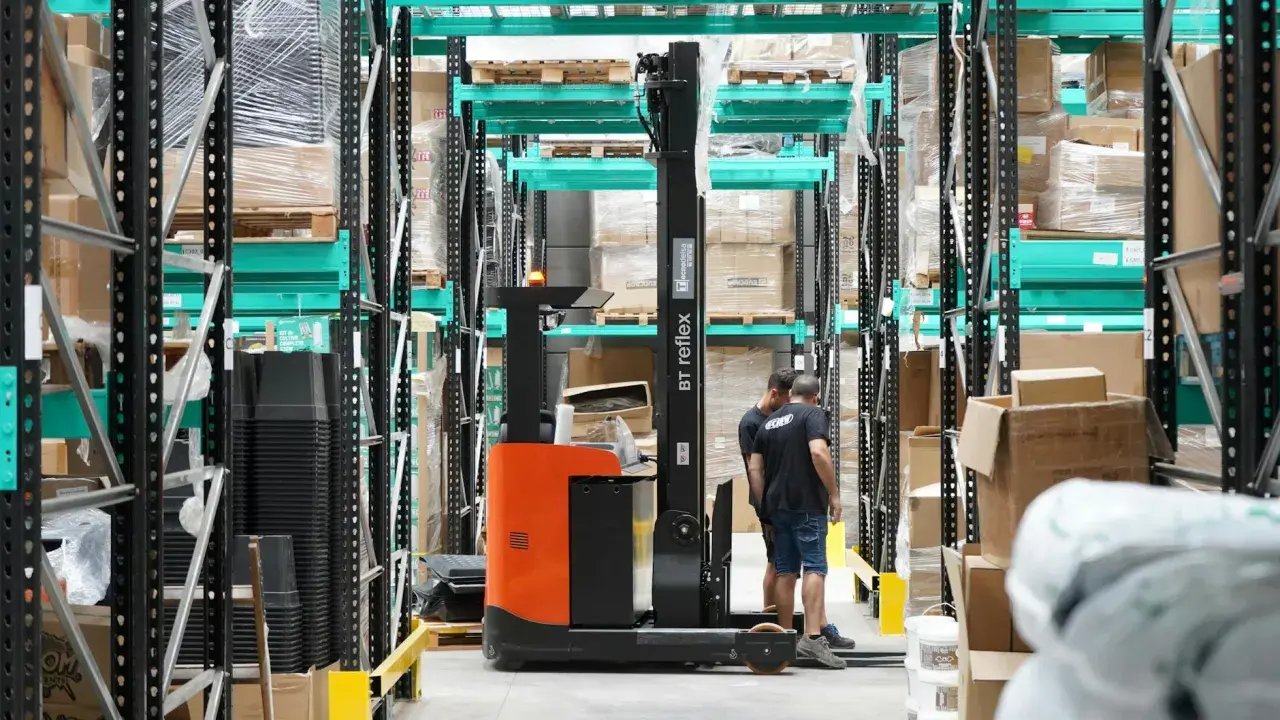 Wózek widłowy w magazynie, pracownicy przygotowują towar do wysyłki. Efektywny outbound logistics.