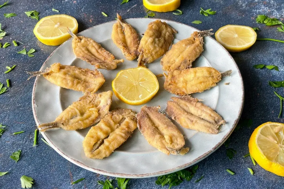 Bocartes fritos crujientes y dorados, servidos en un plato con rodajas de limón y perejil fresco. ¡Un manjar listo para disfrutar!