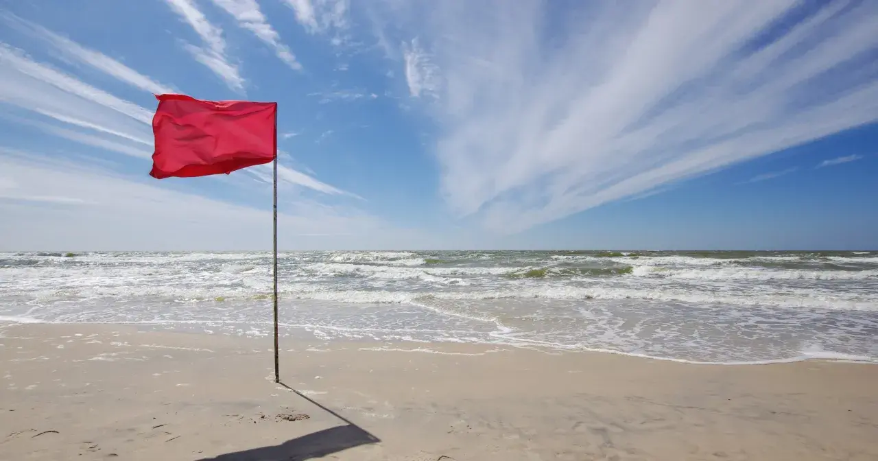 Czerwona flaga na plaży Bałtyku ostrzega przed niebezpiecznymi warunkami. Zamknięte plaże Bałtyk z powodu sztormu.
