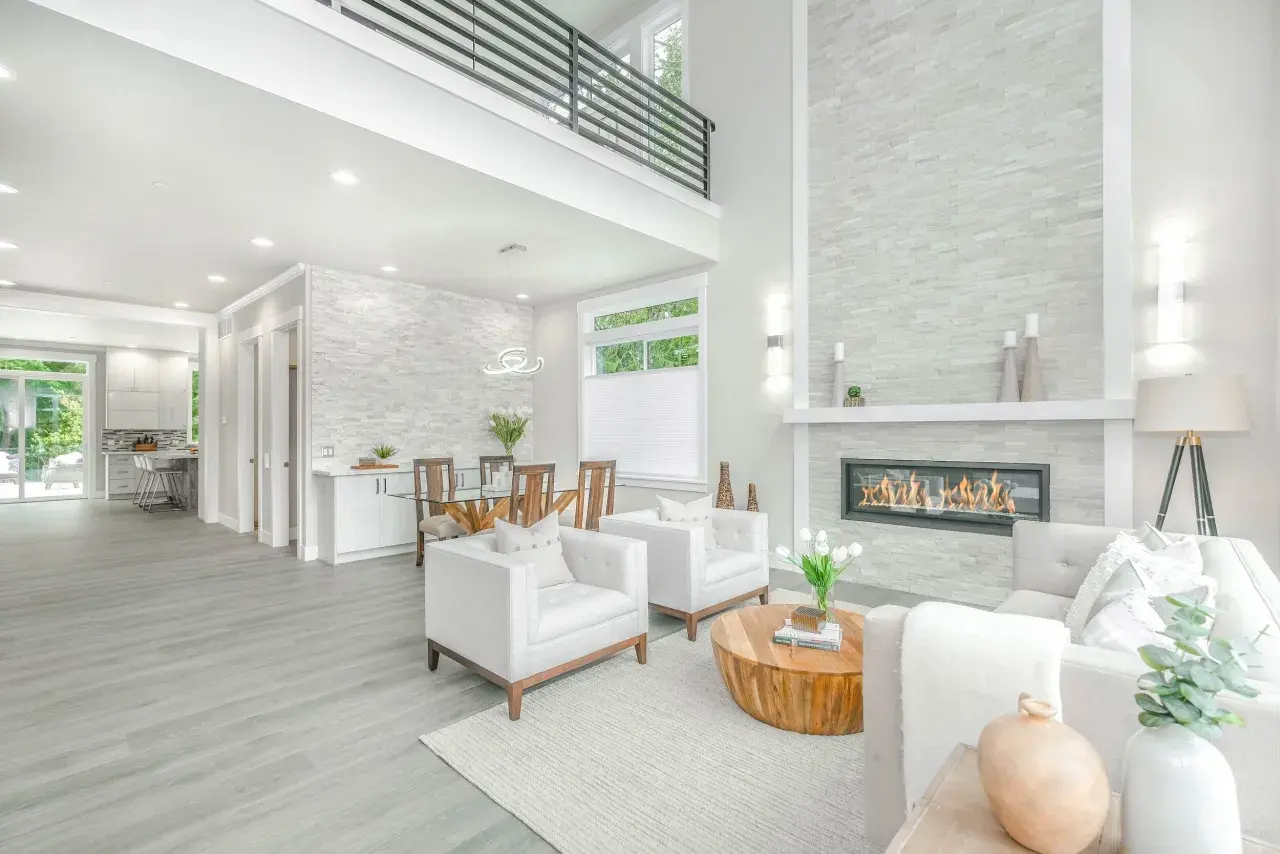 A modern living room with a fireplace, dining area, and kitchen, showcasing a full service interior design.