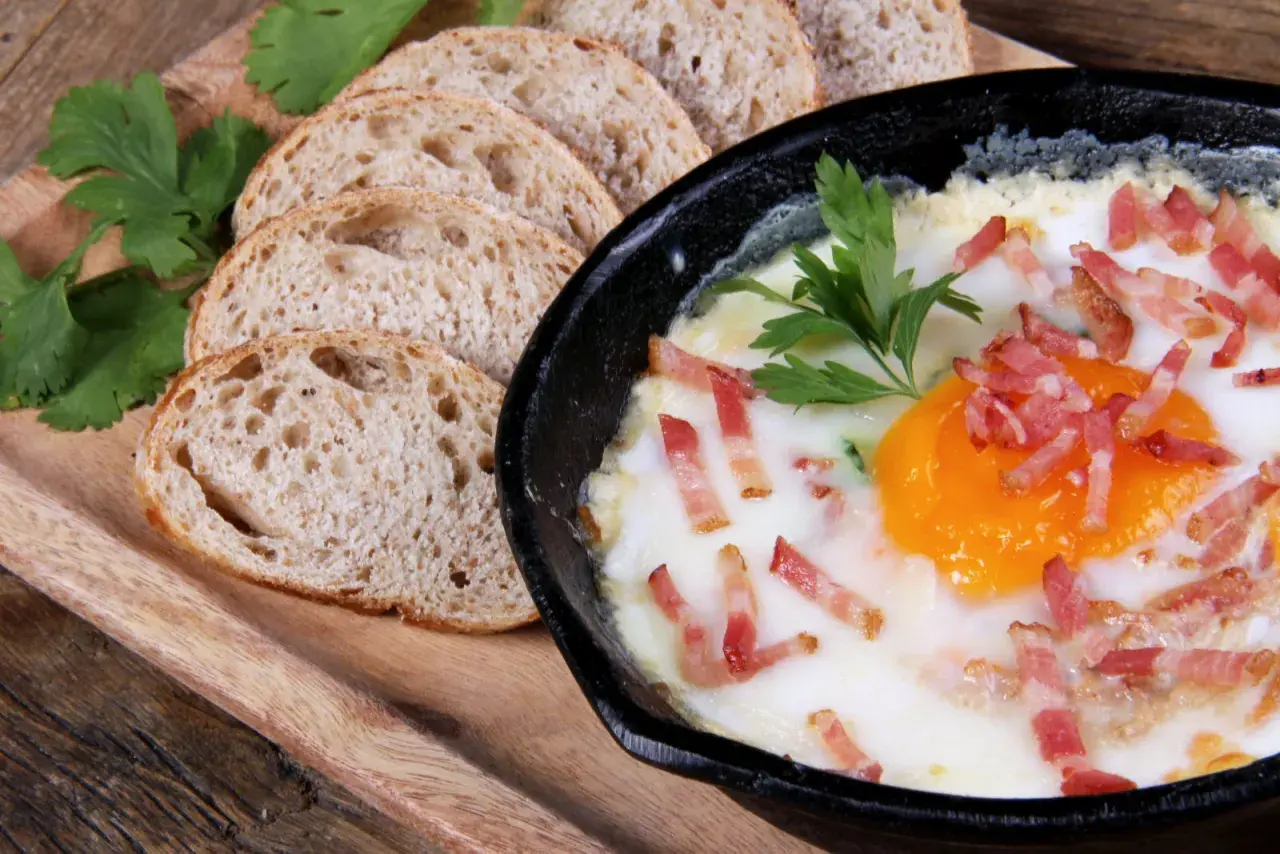 Un délicieux oeuf cocotte, parsemé de lardons croustillants, servi avec des tranches de pain de campagne.