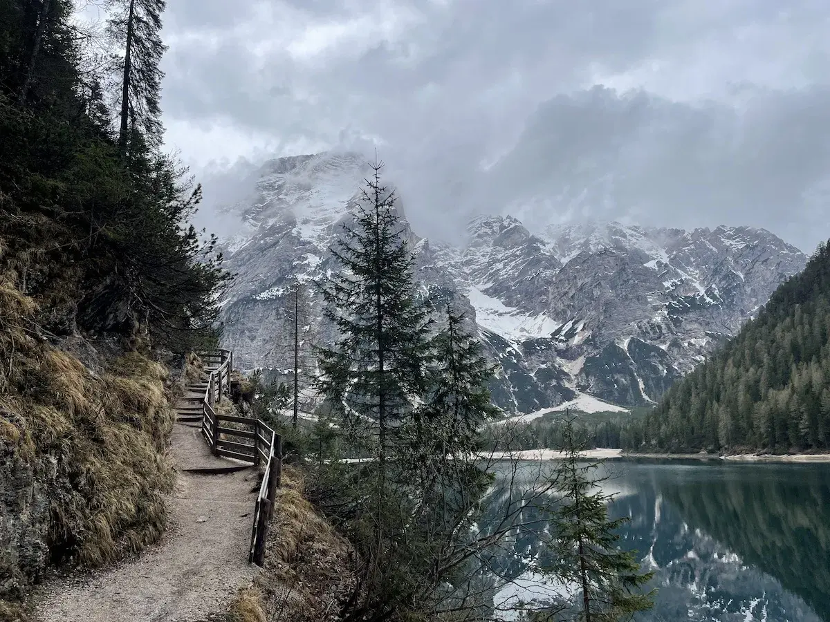 Sentiero da Brunico a Lago di Braies, con montagne innevate e riflessi sull'acqua.