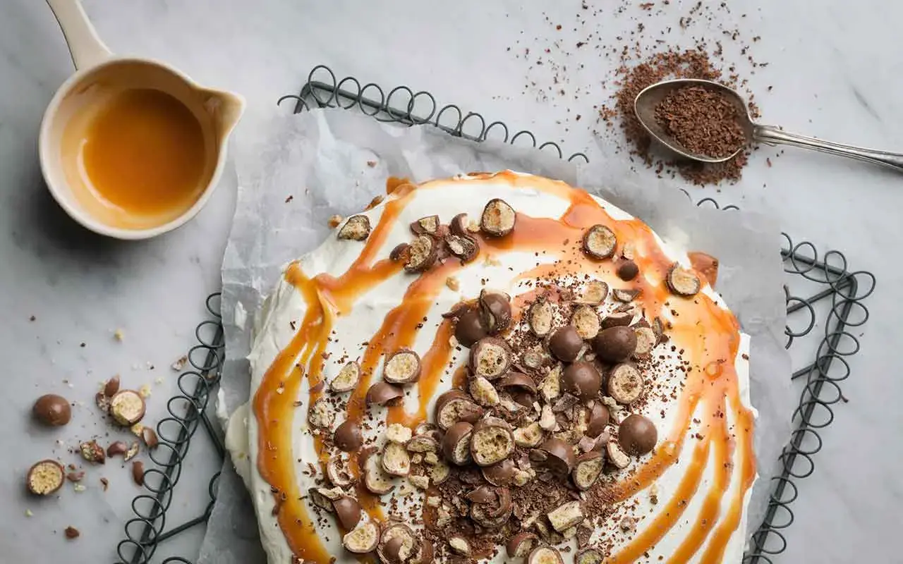 Ein köstlicher Banoffee-Kuchen, dekoriert mit Karamell, Schokostückchen und ganzen Schokokugeln. Perfekt für dein nächstes Banoffee Rezept!