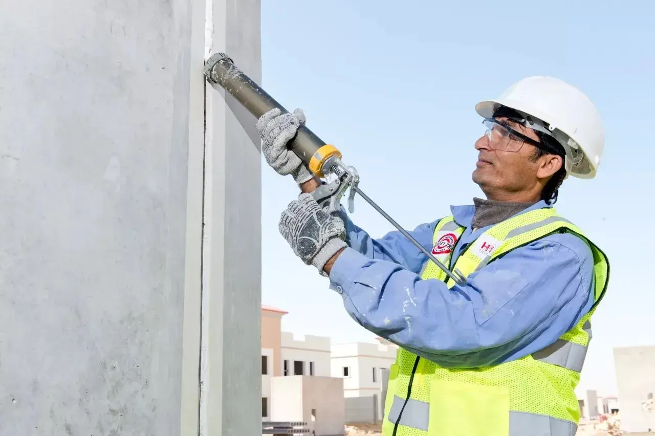 Obrero aplica Sikaflex para sellar juntas en construcción. Este adhesivo es ideal para unir y sellar materiales, asegurando durabilidad y resistencia.