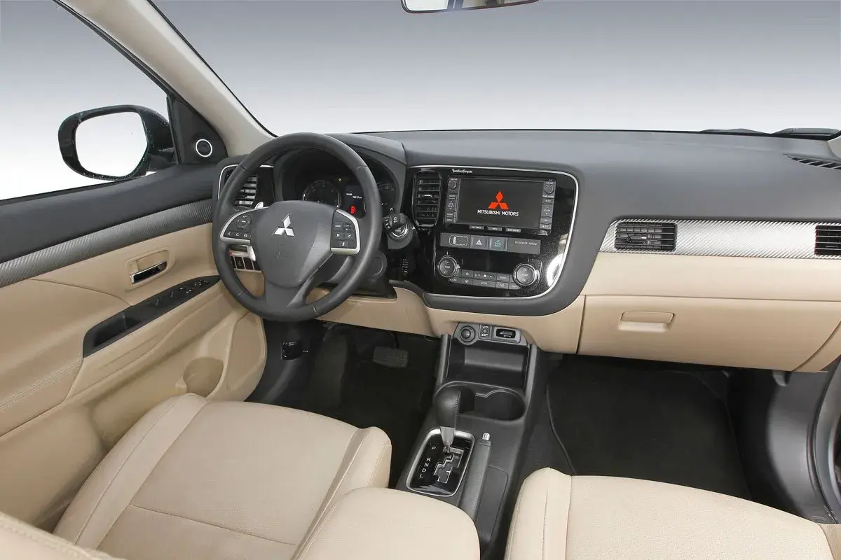 Interior de Mitsubishi Outlander 2.2 Di-D 150. El tablero, asientos y consola central beige sugieren un coche bien cuidado, a pesar de posibles problemas.