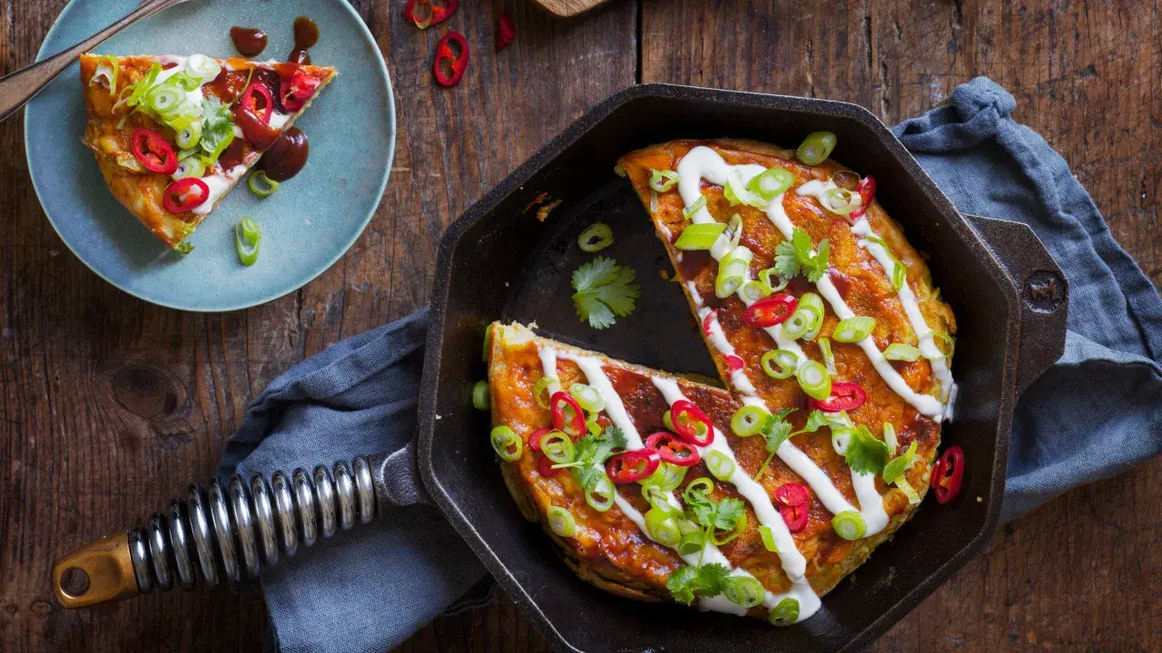 En saftig okonomiyaki i gjutjärnspanna, toppad med gräddfil, salladslök och chili. Ett perfekt recept för en smakrik middag.