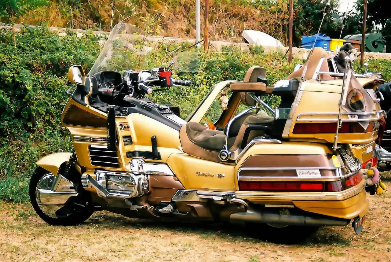 Złoty motocykl turystyczny z dużym bagażnikiem i wygodnymi siedzeniami.