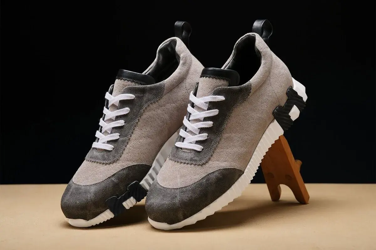 Ein Paar beigefarbene Sneaker mit grauen Akzenten und weißen Schnürsenkeln. Sie zeigen, wie orthopädische Schuhe aussehen können: stilvoll und bequem.
