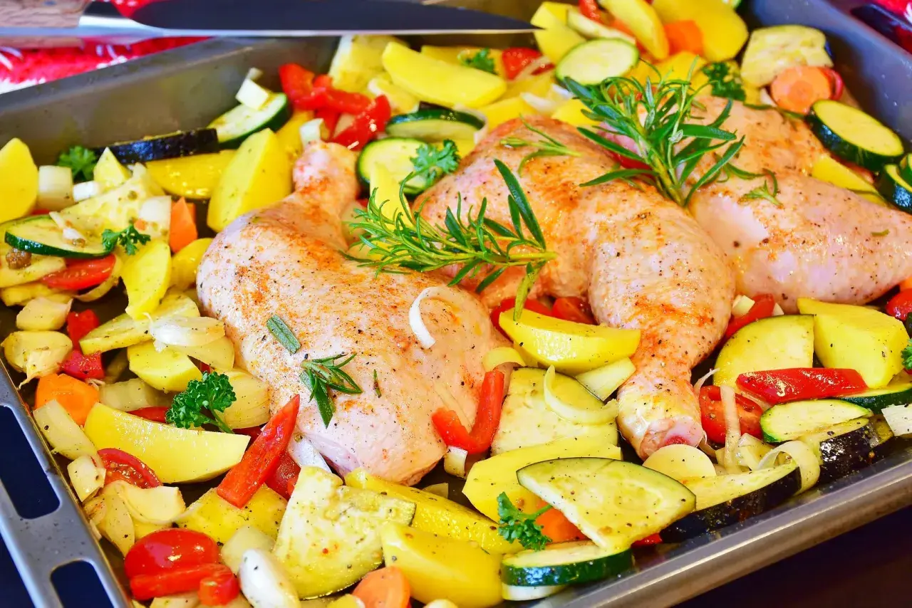Gotowe do pieczenia: pieczone udka z kurczaka z ziemniakami, cukinią, papryką i ziołami.