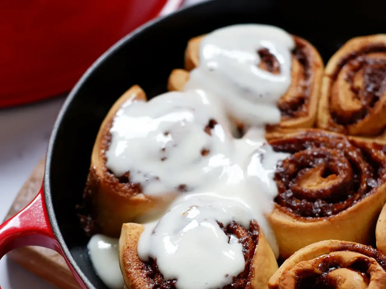 Deliciosos rollitos de canela recién horneados, cubiertos con un glaseado cremoso, listos para disfrutar.